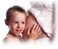 Un petit garçon qui a l'oreille posée sur le ventre de sa mère enceinte.